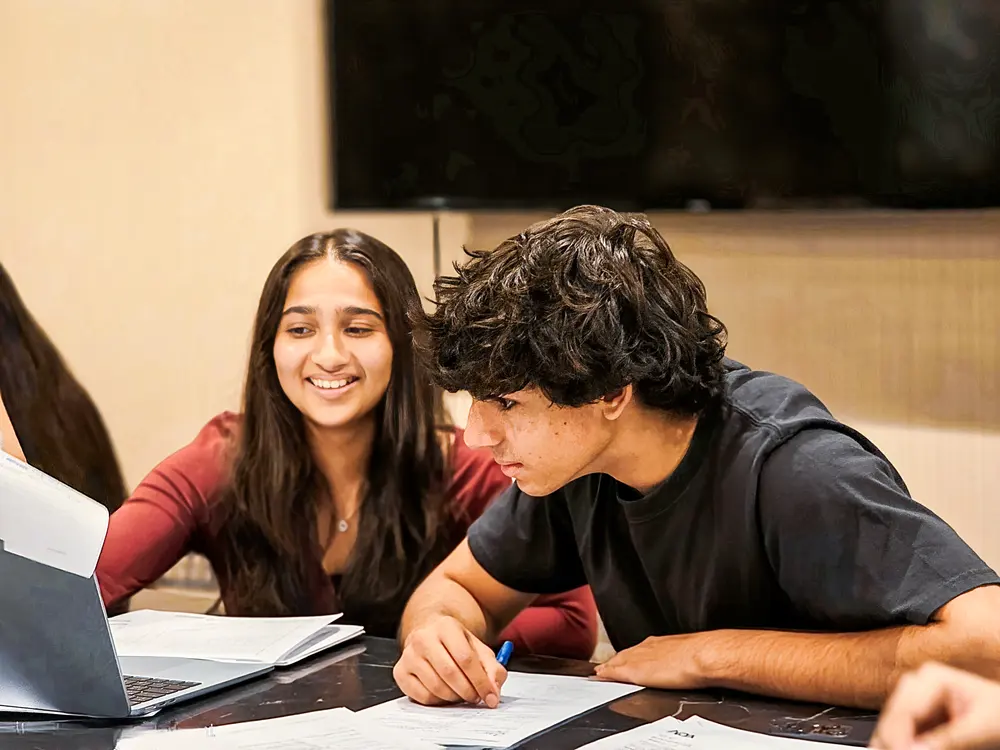 Upper secondary students smiling as they brainstorm in a Chemistry class at Improve ME Institute