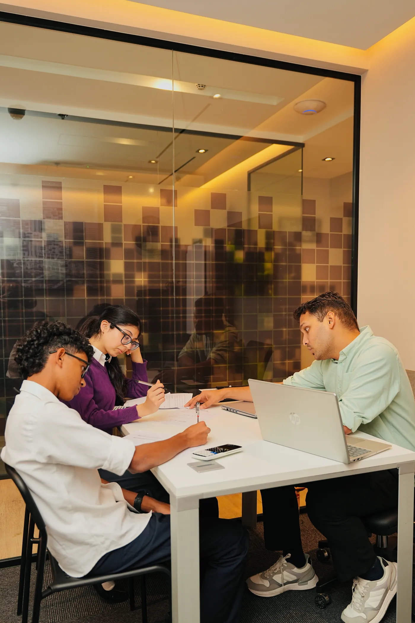 A tutor guiding two students through a problem in a small-group session at Improve ME Institute.