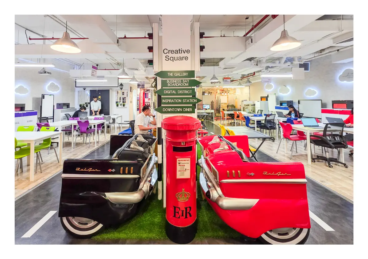 Open-plan primary learning floor with a London post box and vintage car seating at Improve ME Institute