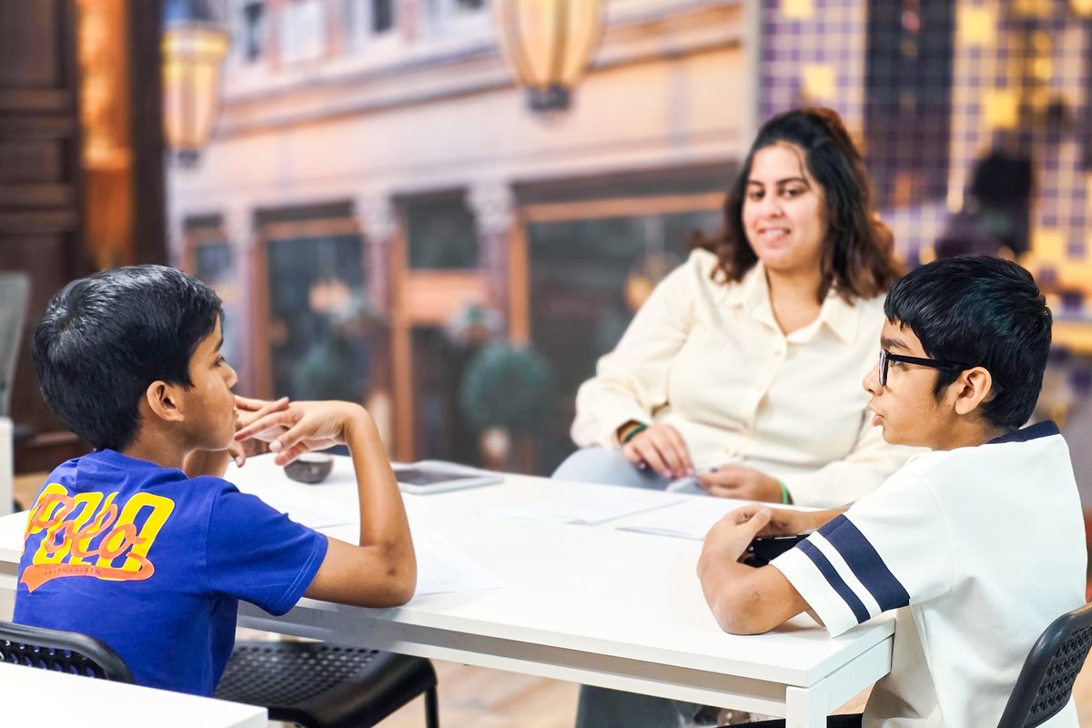 A tutor and two boys reviewing schoolwork together at a table at Improve ME Institute in Dubai.