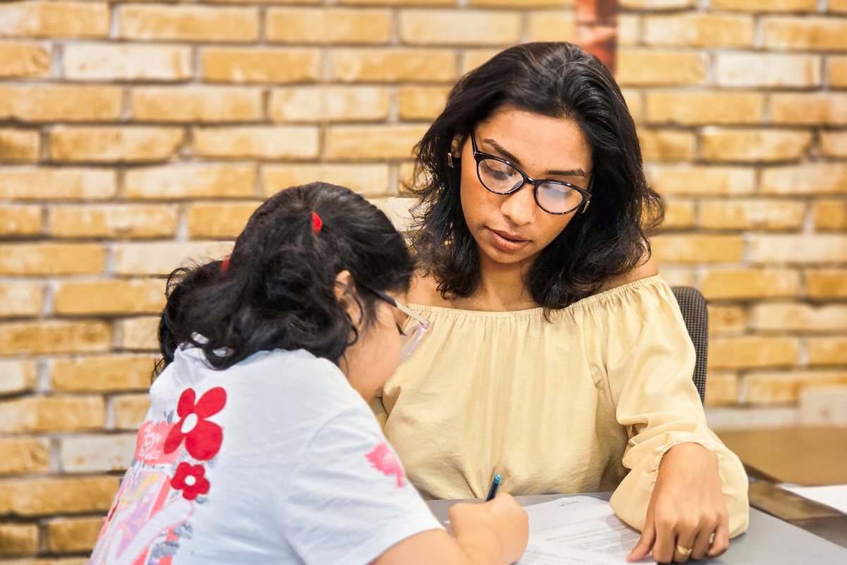 Woman teaching science to a young boy at home with a microscope.