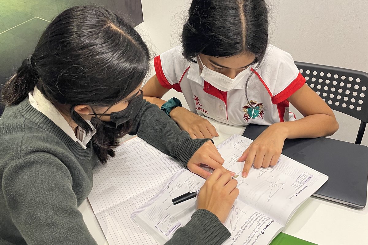 Two students in school uniform working through a worksheet together at Improve ME Institute in Dubai.
