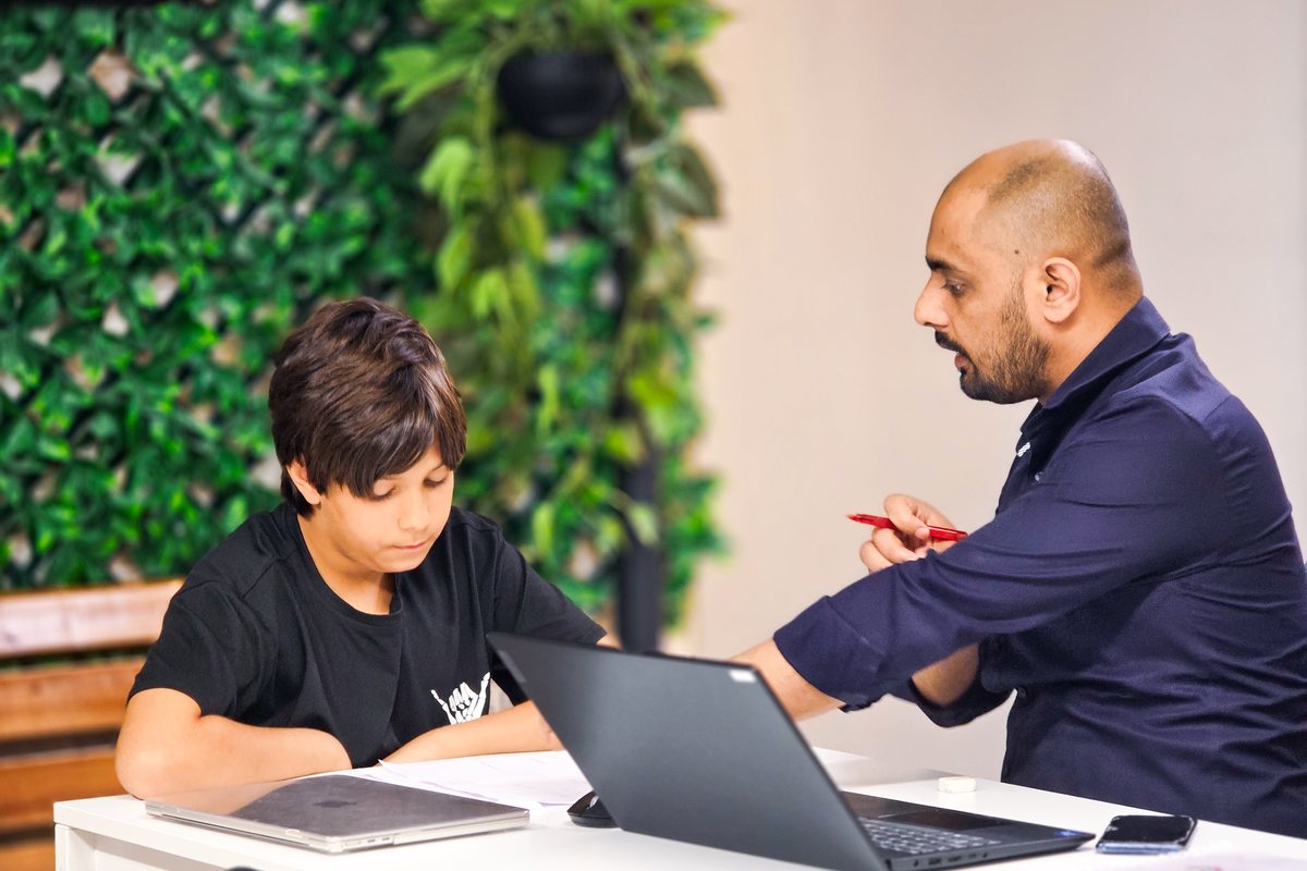 A tutor giving one-to-one support to a student on a laptop at Improve ME Institute in Dubai.