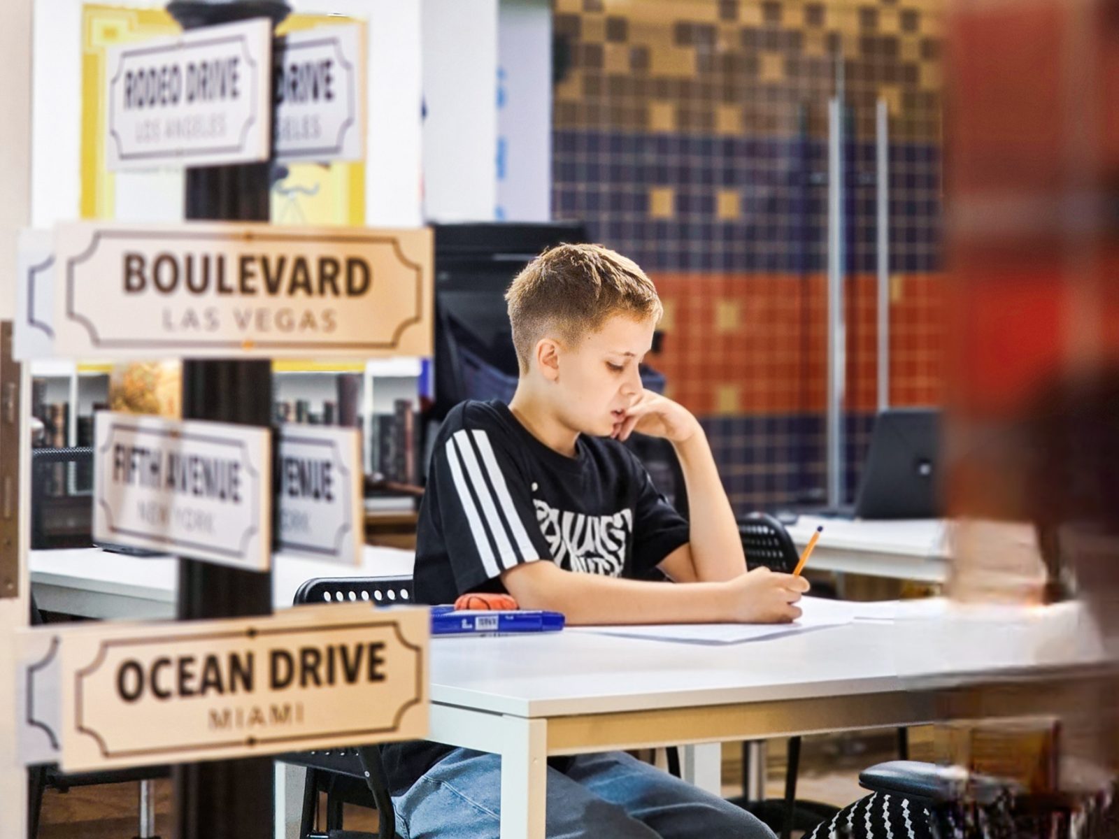 A student concentrating on a written task at a desk in a study room at Improve ME Institute in Dubai.